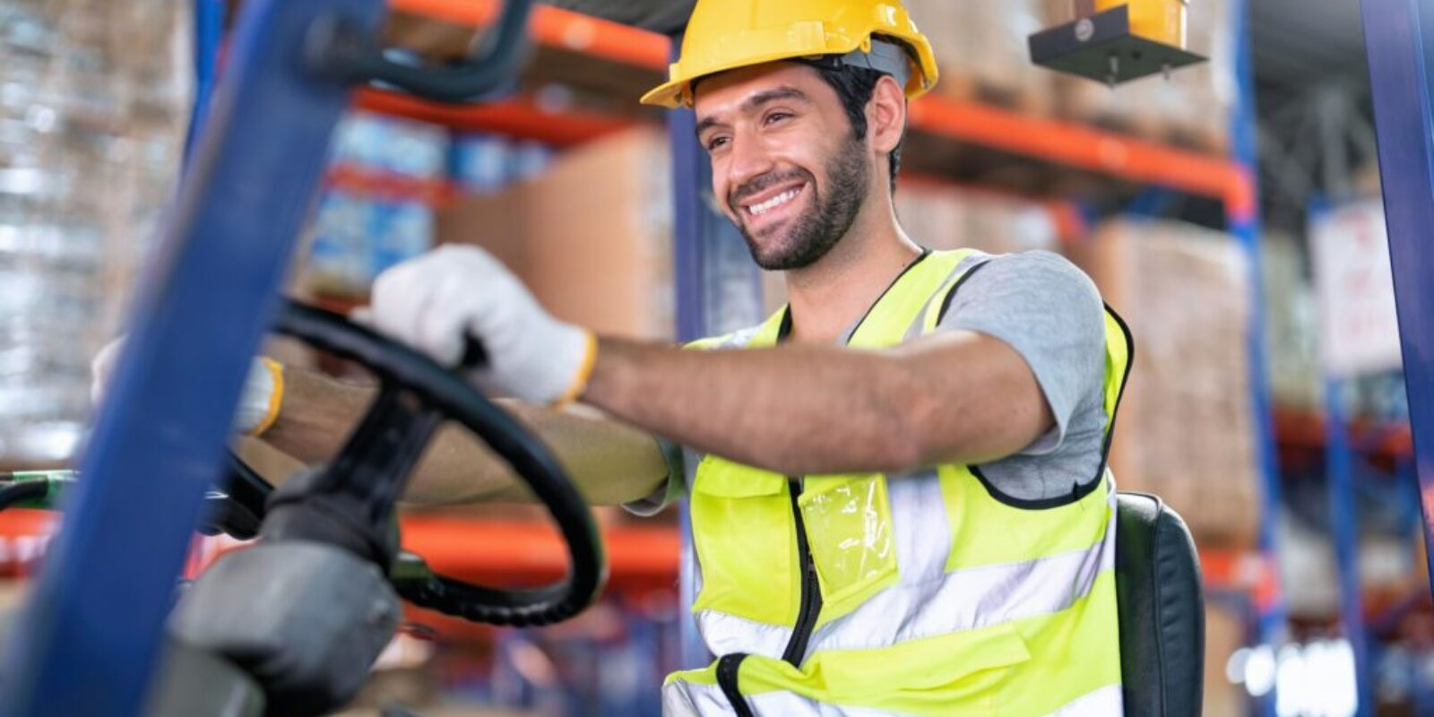 Forklift Truck Operator Lifts Pallet Cardboard Boxes On a Shelf by Trucks smiling portrait